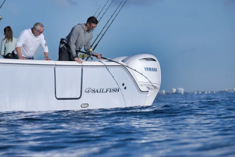 Two men on a white sport fishing boat leaning over the side with fishing rods ready to cast, Yamaha engine visible at the stern