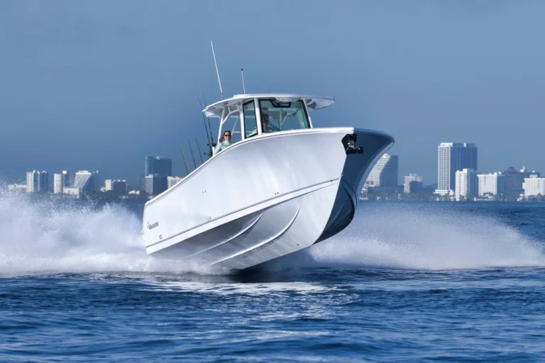 White speedboat zooming across blue water with a distant city skyline in the background.