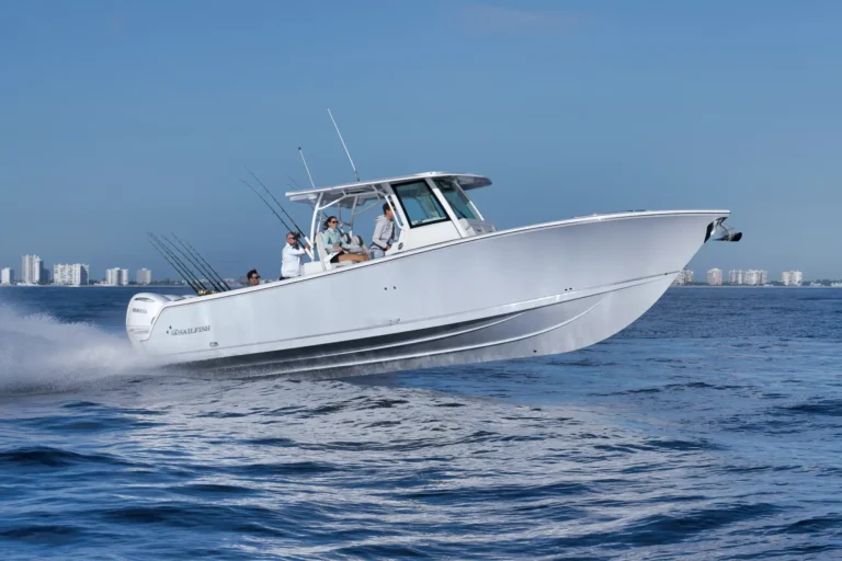 White motorboat speeding on blue water with passengers and fishing rods, city skyline in the distance.