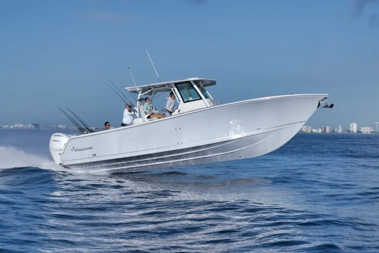 White high-speed fishing boat with multiple passengers slicing through blue water, urban skyline in the background.