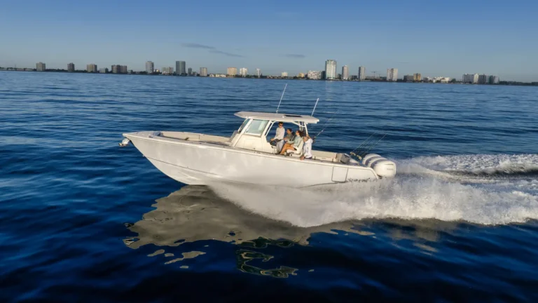 White motorboat speeding through blue water with a city skyline in the background, four people on board. - Informative image: coastal city view with a fishing boat in motion.