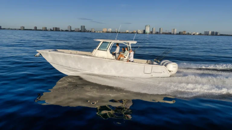 White motorboat with four people fishing on calm blue water, city skyline in the distance