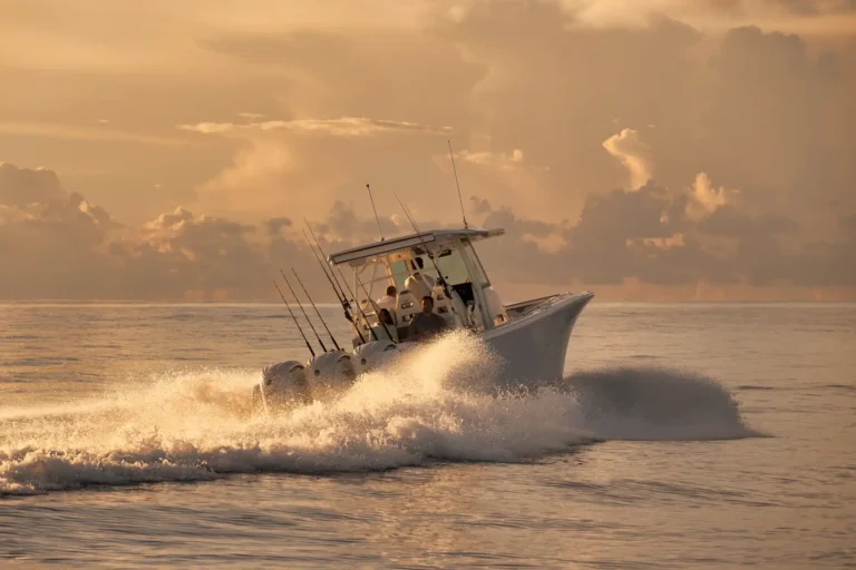 A white motorboat skims through sunlit waves at sunset, rods mounted on the sides and spray spraying from the bow.