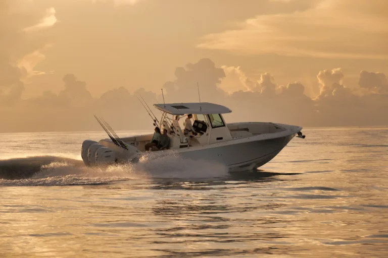 White motorboat speeding across the sea at sunset, with fishing rods mounted and passengers on deck.