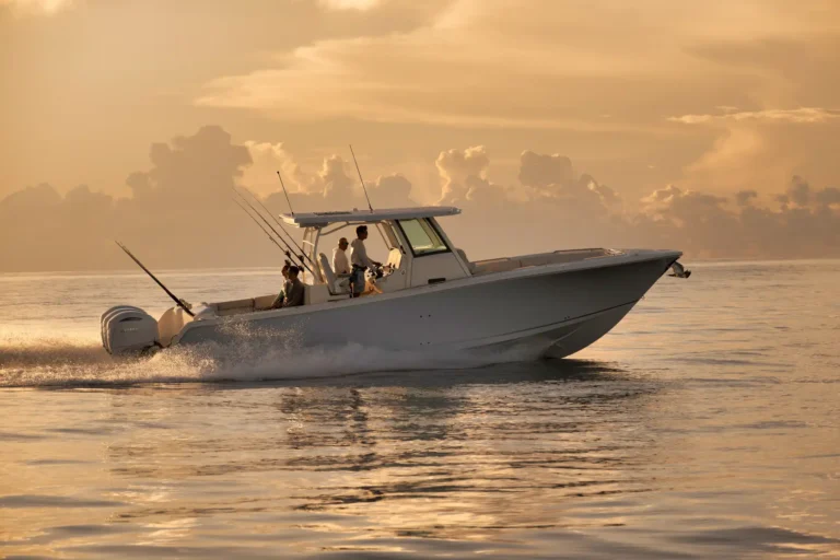 White powerboat speeding on calm water at sunset with three people fishing on the deck.