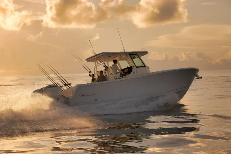White sportfishing boat speeding over calm water at sunset, fishing rods lined along the stern.