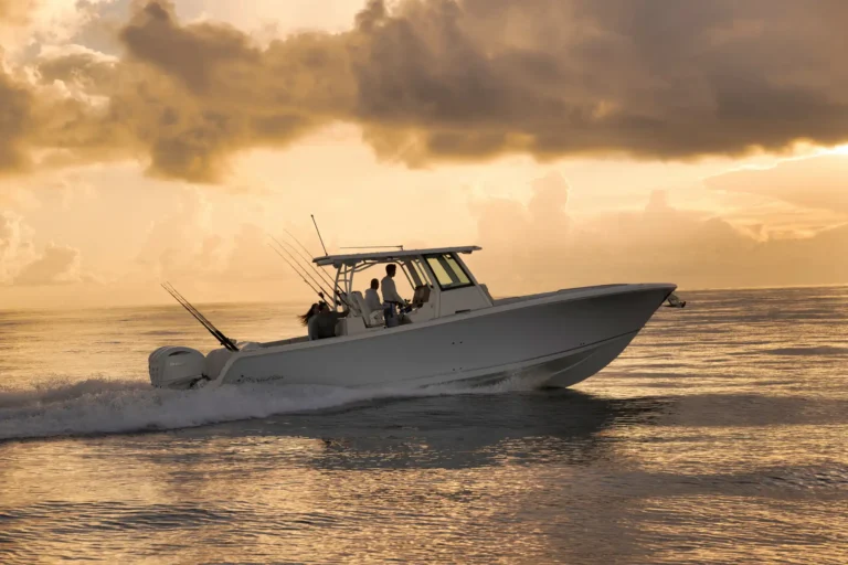 White motorboat with several people fishing at sunset on calm water.