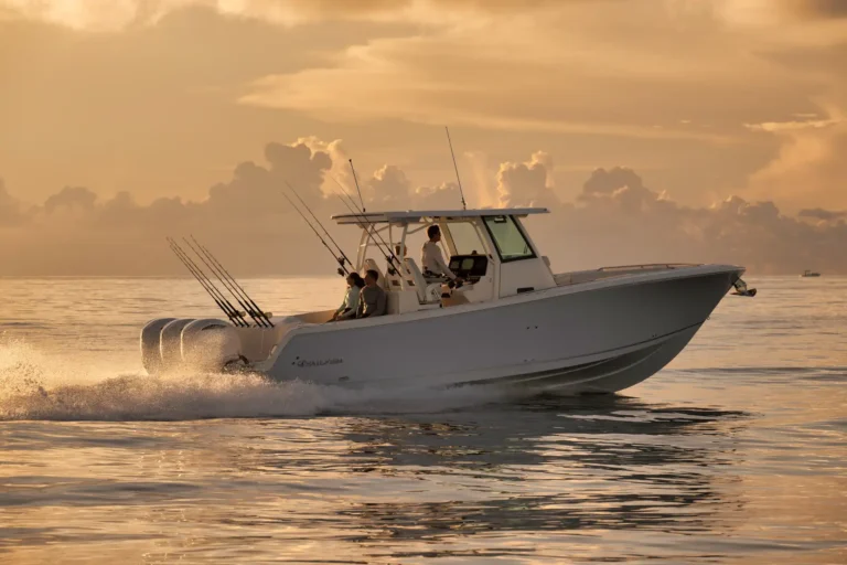 White sport fishing boat speeding across calm water at sunset with multiple fishing rods mounted along the stern side.