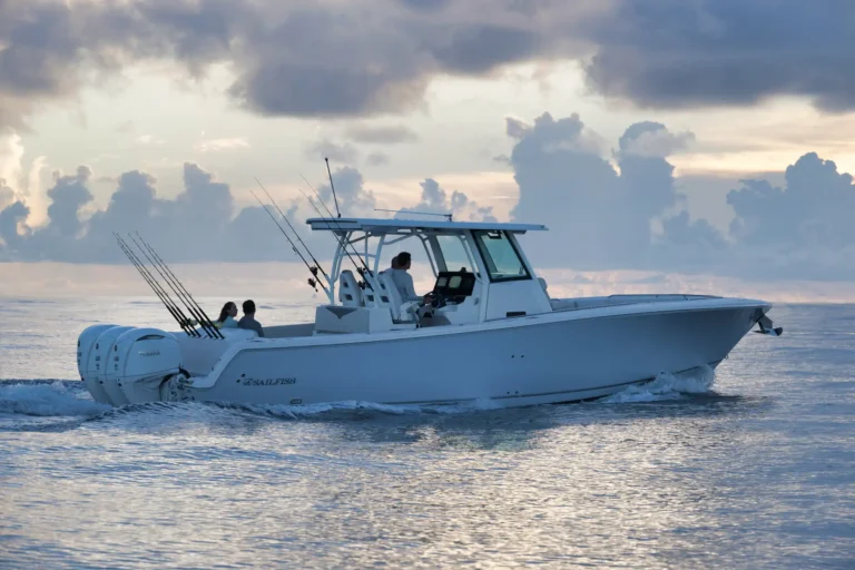 White sport fishing boat on calm water with multiple fishing rods in rod holders and two people seated at the stern, cloudy sky above