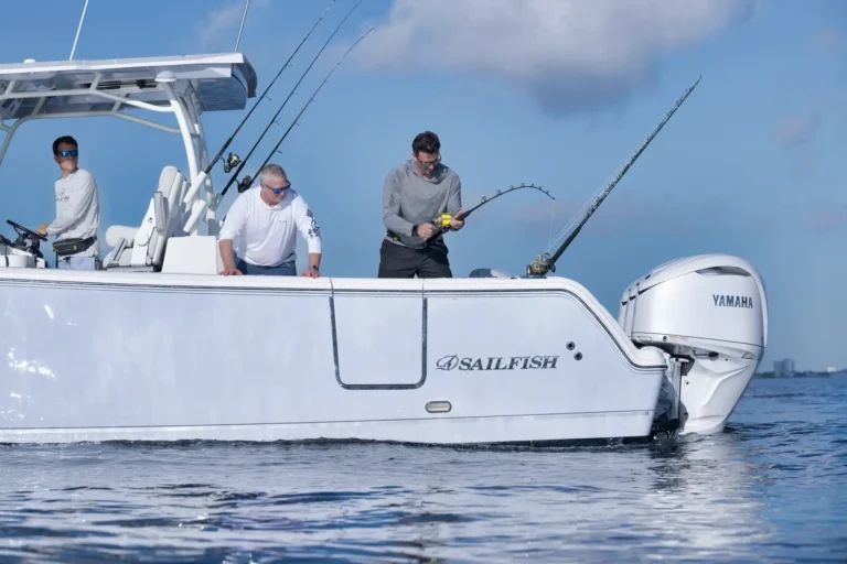 Three anglers on a white sport boat with multiple fishing rods and a Yamaha outboard engine, fishing at sea.