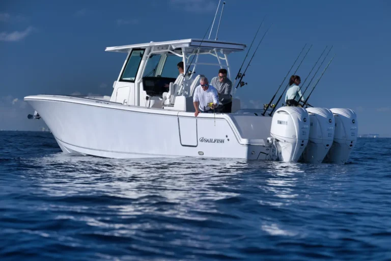 White sport fishing boat on calm blue water with several fishing rods mounted at the stern and crew handling gear.