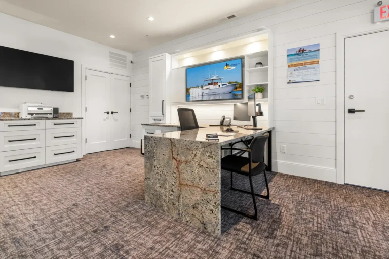 Reception area with a granite desk, black chairs, and a wall-mounted TV showing a boat image on the screen