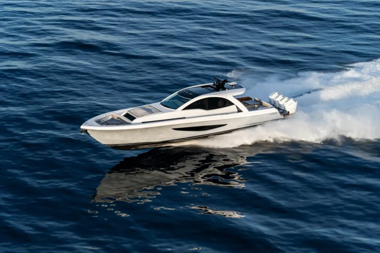 White speedboat racing across dark blue ocean, leaving a white wake behind it.