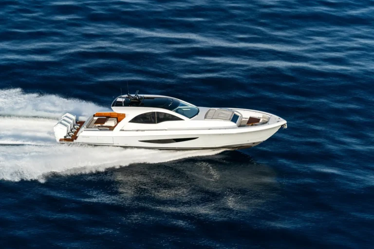 White luxury motor yacht speeds across deep blue ocean, leaving a white frothy wake behind it.