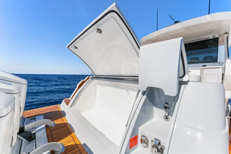 Open hatch on a white luxury yacht with teak deck and ocean in the background on a clear day
