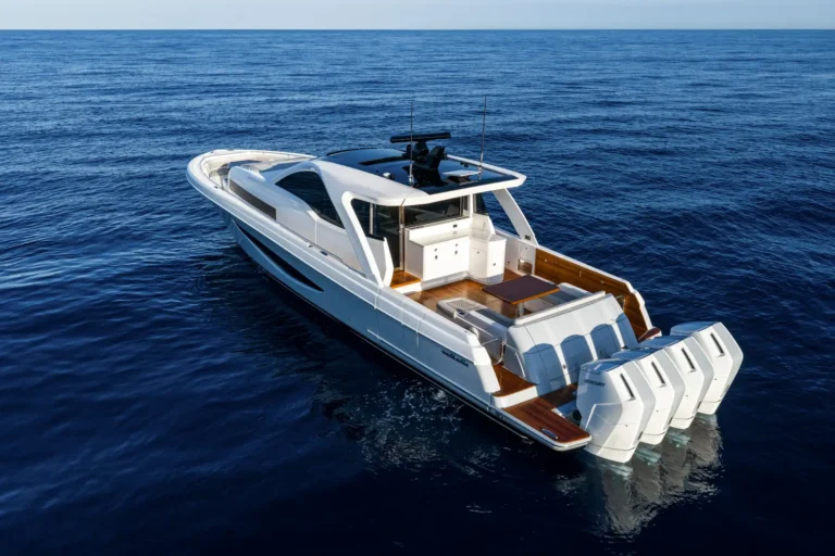 A white luxury motor yacht viewed from above sailing on calm deep blue ocean water.