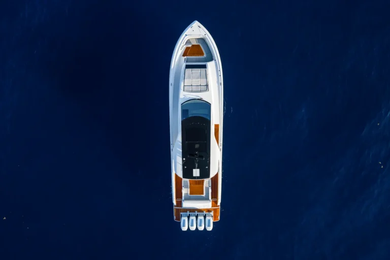 Aerial view of a white motorboat seen from above on deep blue water.