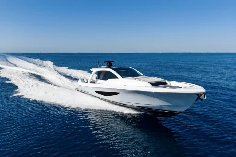 White speedboat speeding across open blue ocean, leaving frothy wake behind.