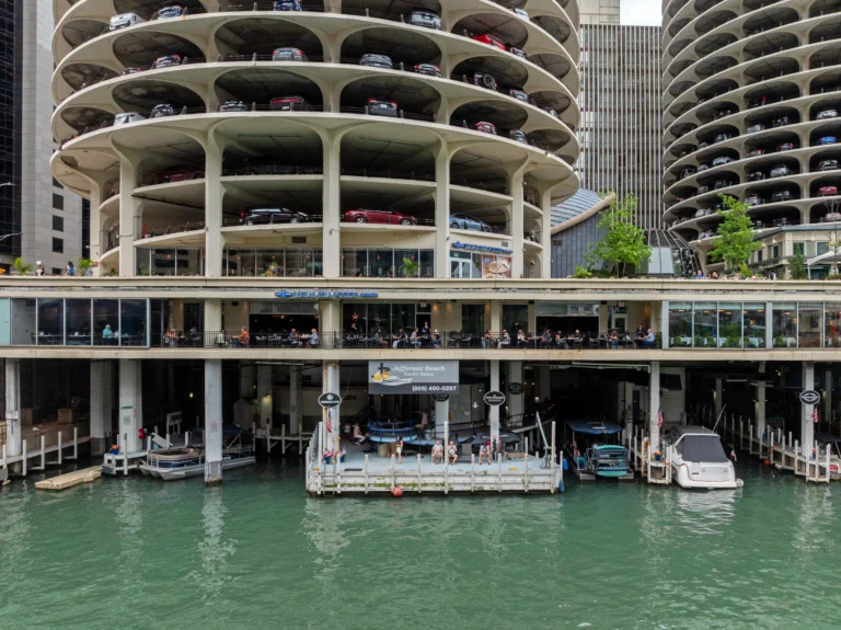 Spiral multi-level parking garage by a marina with cars on all levels and boats in the water below