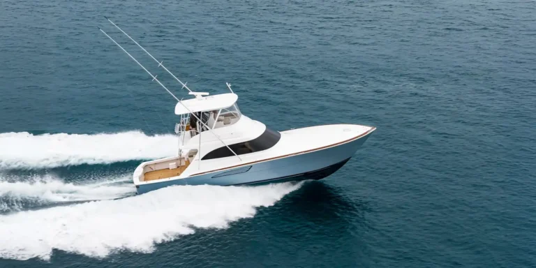 White sport yacht speeding across blue ocean, leaving white wake behind.