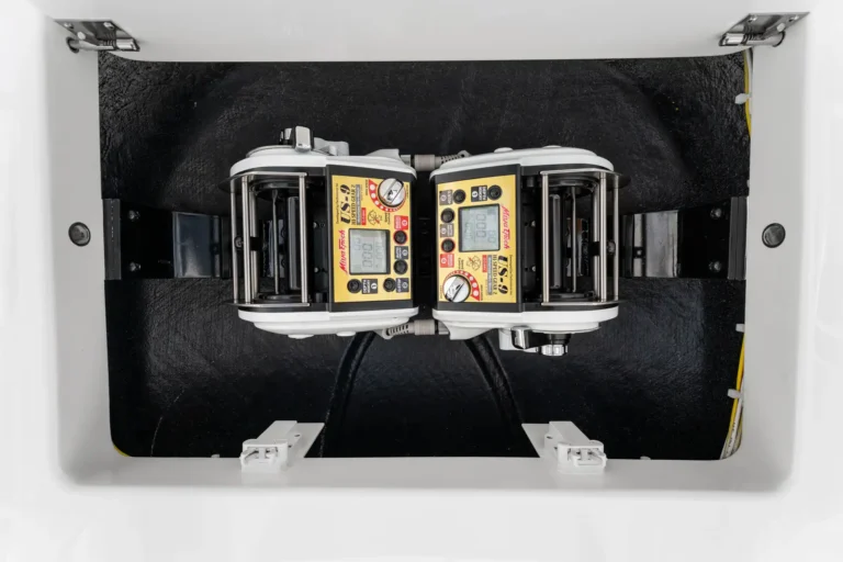 Two identical electronic control units with yellow fronts mounted side by side inside a white cabinet interior.