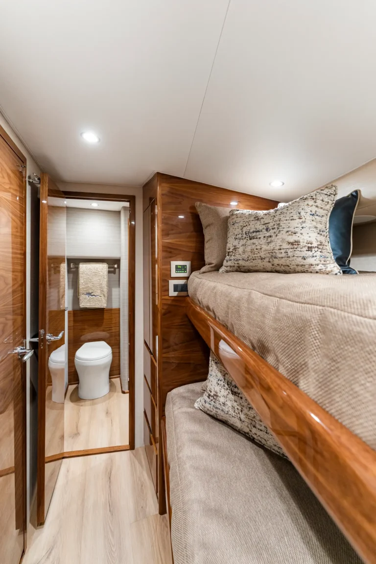 Narrow cabin with two-tier bunk bed on the right and a small bathroom with a toilet at the far end.