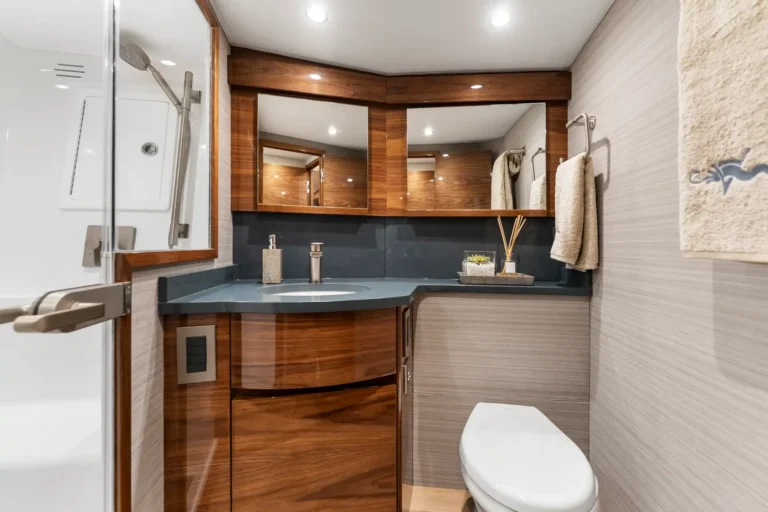 Modern bathroom with a wood vanity, large mirror cabinet, and beige-tiled walls; towels hang on the right. (informative)