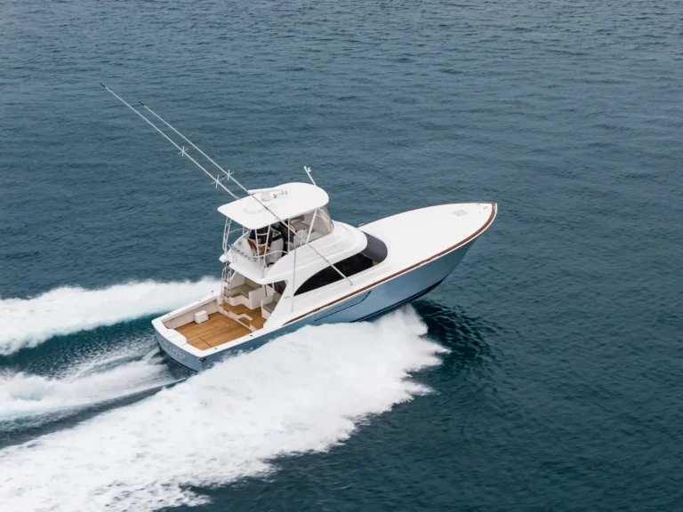 White motorboat speeding across blue ocean, leaving a white frothy wake behind.