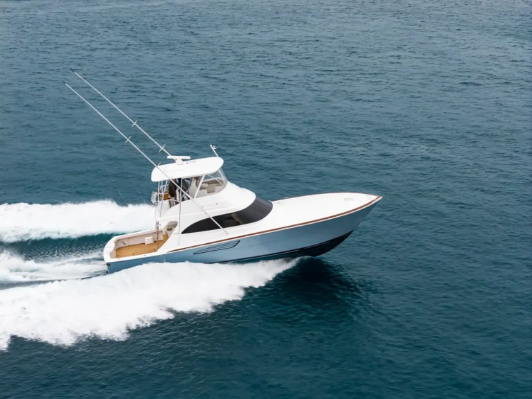 White speedboat cruising at high speed on blue ocean water, creating a white wake behind it