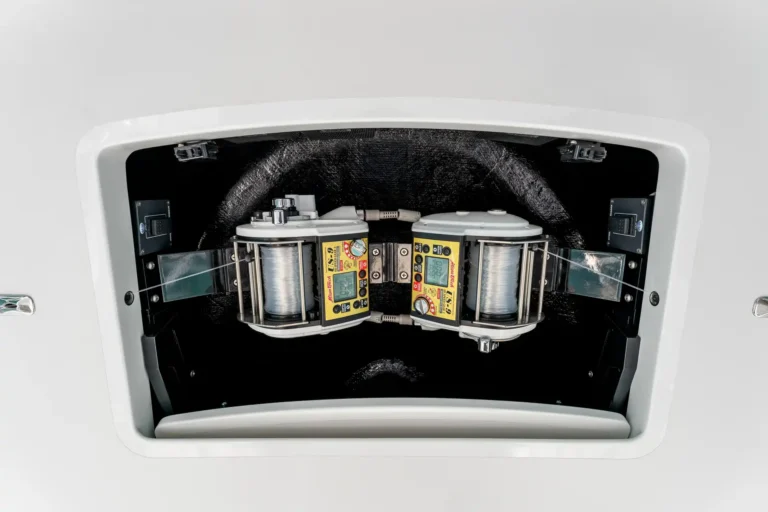 Open hatch reveals two labeled control modules with digital displays, gauges, and coiled wires inside a white appliance chamber