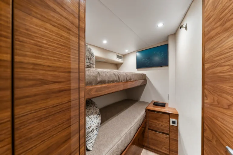 Cozy wood-paneled bunk cabin with a lower bunk, flat-screen TV on the far wall, and a small nightstand.