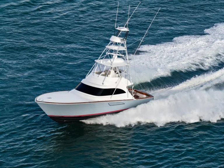White luxury speedboat cutting through deep blue ocean, white foam trailing behind the hull.