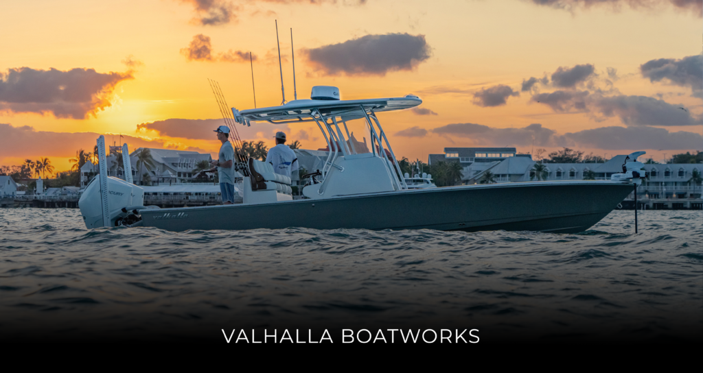 Sport boat on calm water at sunset with a marina and buildings in the background; VALHALLA BOATWORKS text visible at the bottom edge.