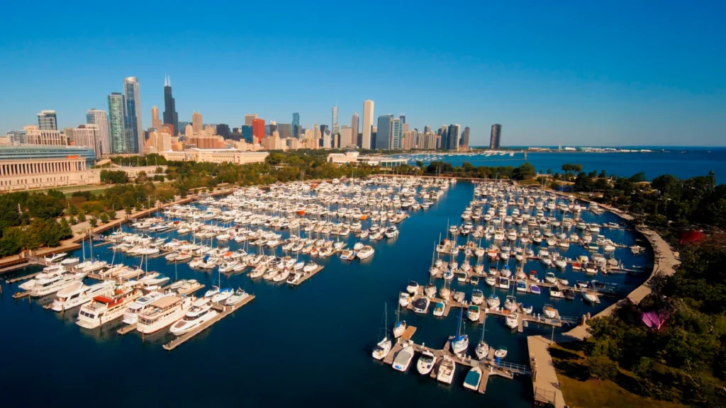 City skyline above a large marina filled with numerous docked boats and calm blue water.